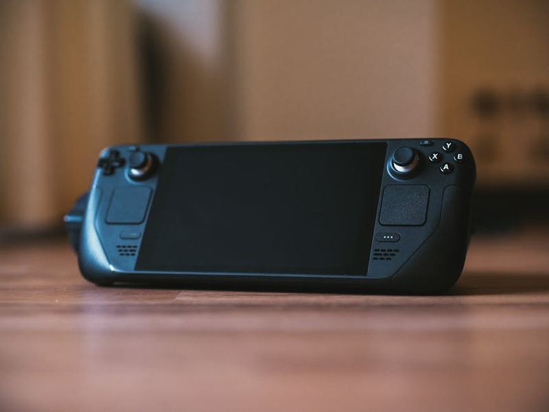 Modern handheld gaming console with buttons and joystick on a wooden surface, ideal for portable gam