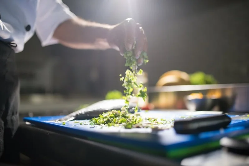 Chef préparant un plat avec des légumes frais et locaux dans une cuisine de restaurant durable