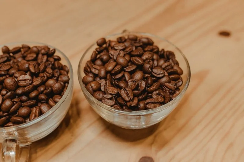 Différents types de grains de café (Arabica, Robusta) sur une table en bois