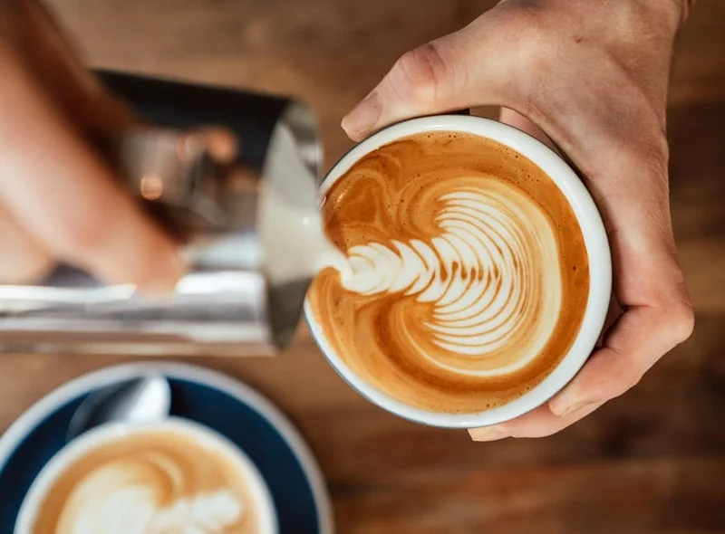 Barista réalisant un latte art avec du lait d'avoine