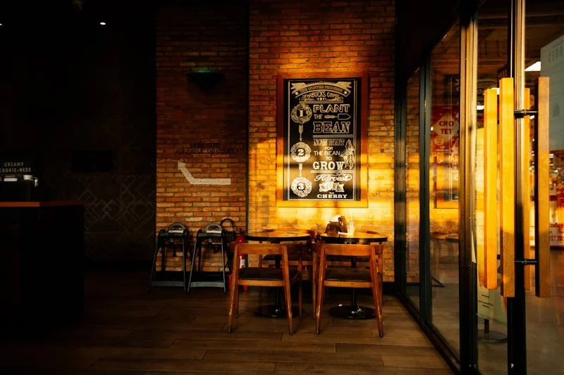 Intérieur cosy et rustique-chic d'un coffee shop avec murs en briques et tables en bois, Lyon