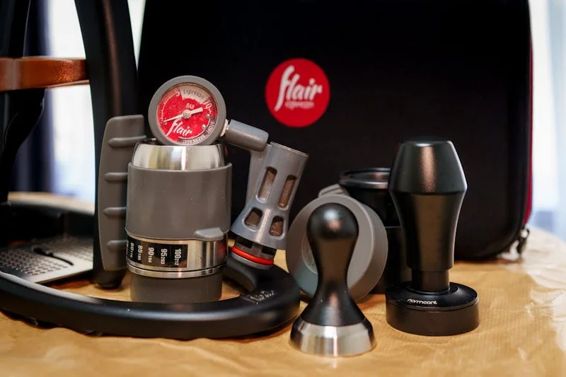 Accessoires de barista incluant une balance de précision, un tamper, un pichet à lait et un outil WDT