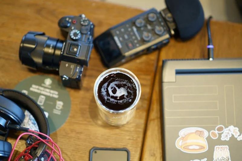 Bureau d'un télétravailleur dans un coffee shop avec ordinateur portable, casque à réduction de bruit et café
