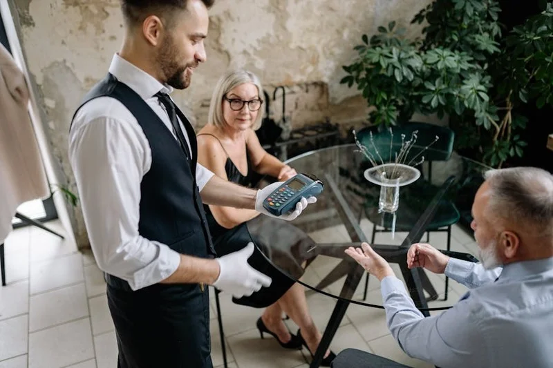 Une personne payant l'addition avec une carte de crédit à une table de restaurant, montrant un cadre de repas soigné